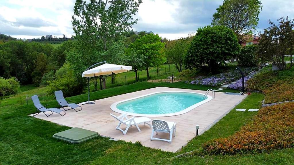 VignaleLa Casa nel Vento的一个带两把椅子和遮阳伞的游泳池