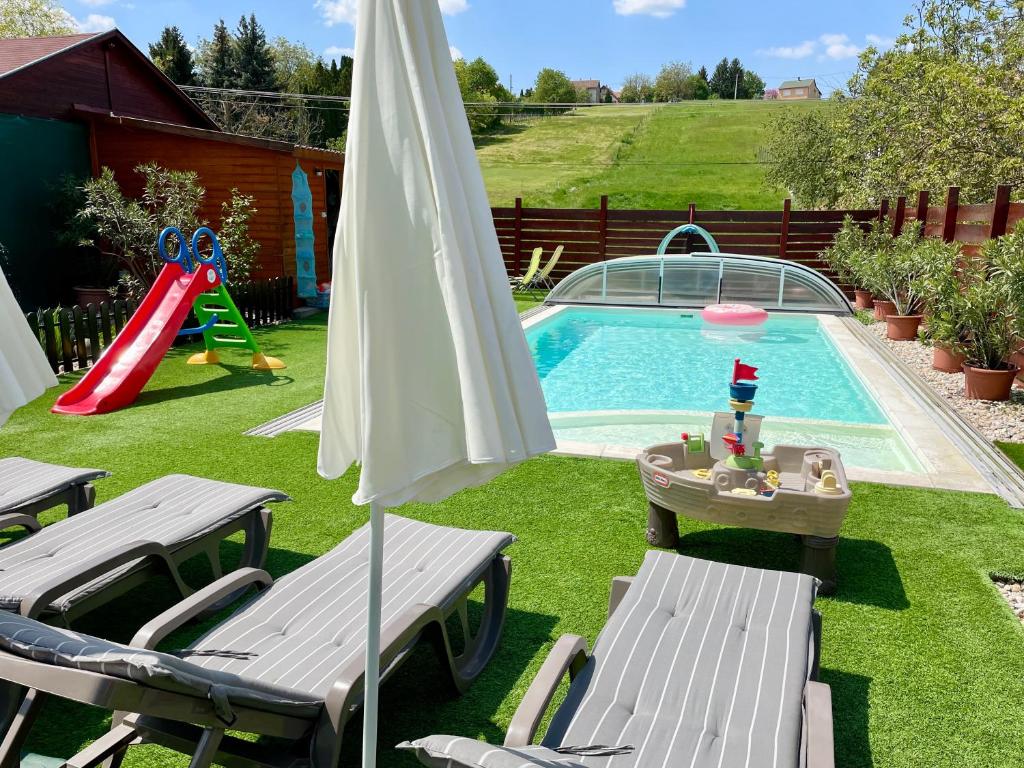 佐洛卡罗斯Mese Panzió Zalakaros的后院设有带滑梯和遮阳伞的游泳池