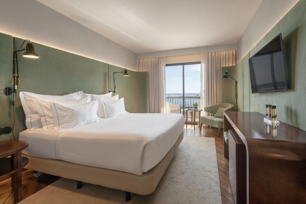 蓬塔德尔加达大西洋亚速尔格兰德酒店的卧室配有一张白色大床和电视。