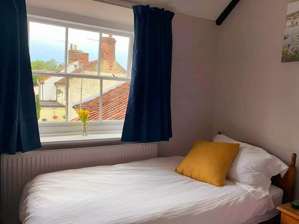 诺里奇The Bell Inn的一间卧室配有床和蓝色窗帘的窗户