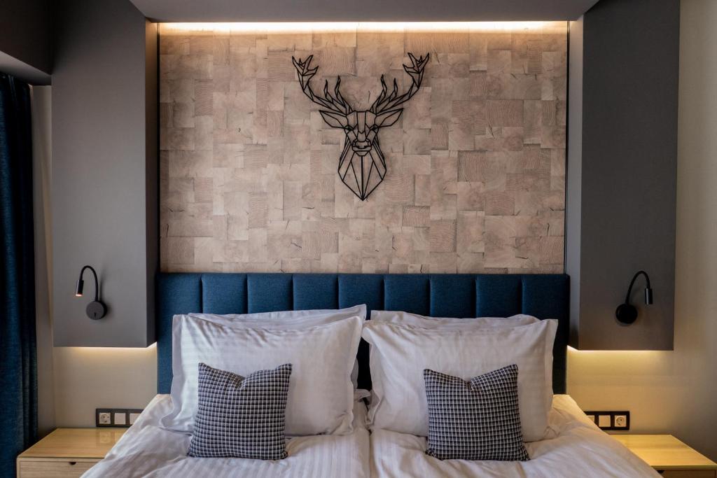 鲁塞City Art Luxury Living Free Parking的一张带白色枕头的床和一个带鹿头的墙壁
