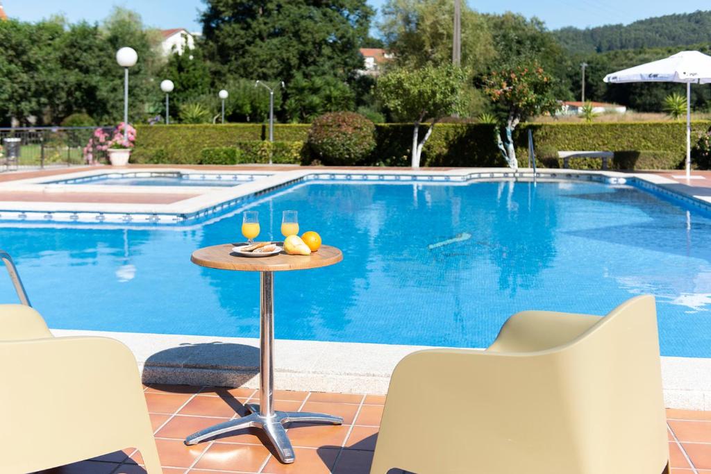桑亨霍卡博费斯提纳匝酒店的游泳池旁的桌子上放着两杯葡萄酒
