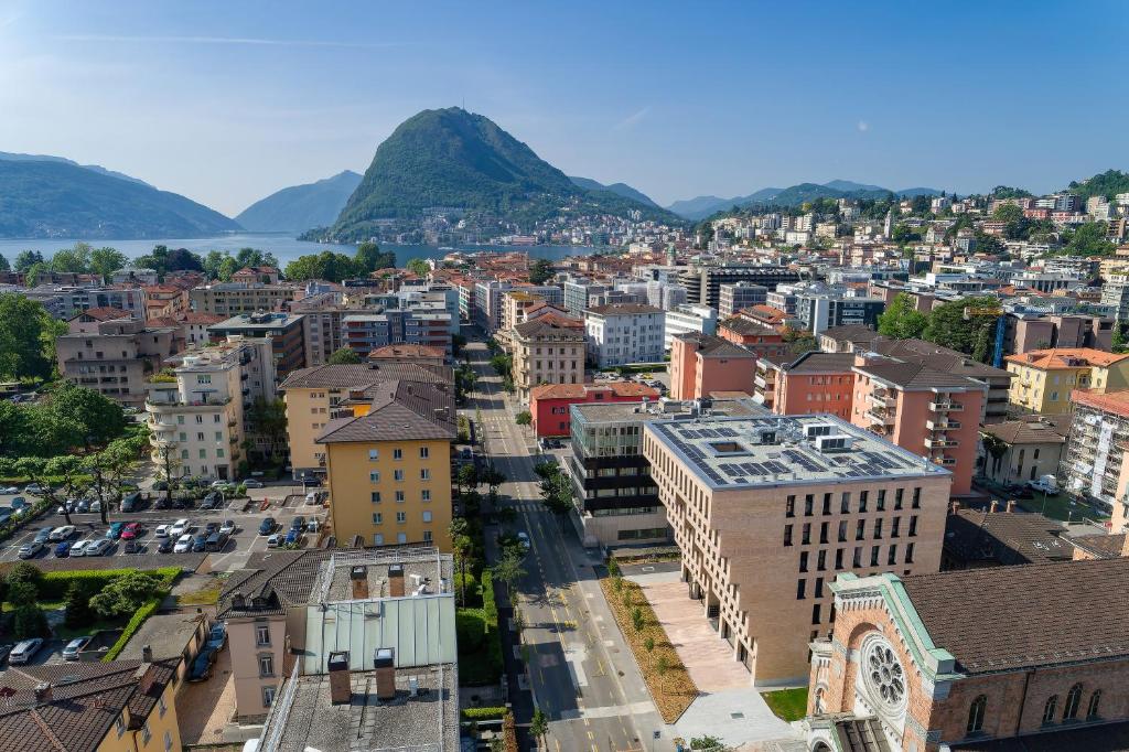 卢加诺Swiss Hotel Apartments - Lugano的城市的空中景观,背景是群山
