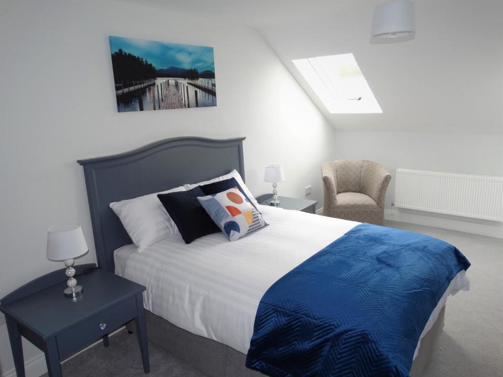CastlepollardLir Lodge的一间卧室配有一张带蓝色毯子和椅子的床
