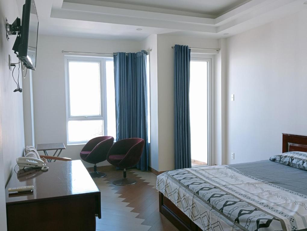 头顿Anh Truc House - Near Front Beach的一间卧室配有一张床、一张书桌和两个窗户。