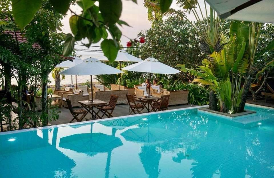 白马市米莉亚度假酒店的一个带桌椅和遮阳伞的游泳池