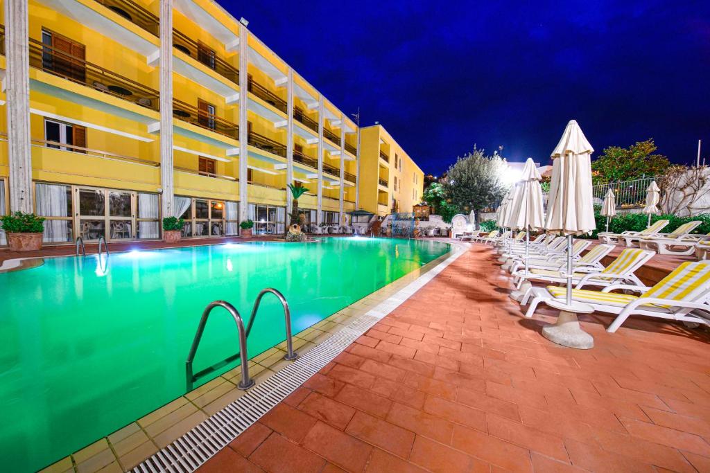 伊斯基亚Grand Hotel Terme di Augusto的酒店旁的游泳池配有椅子和遮阳伞