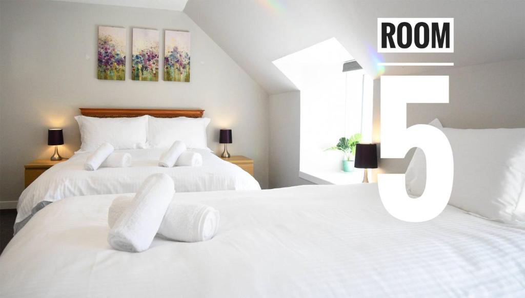 波特里Rooms on the High Street的卧室设有两张白色的床,带有房间标志