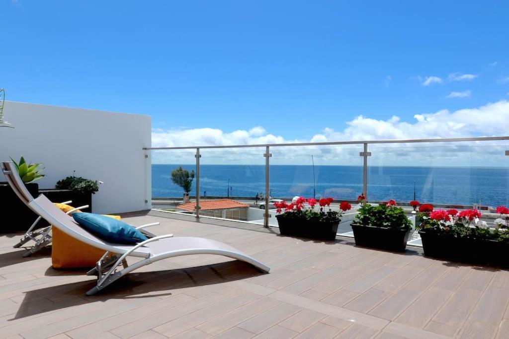 蓬塔德尔加达Consuls Ocean View的一个带椅子和鲜花的甲板和大海