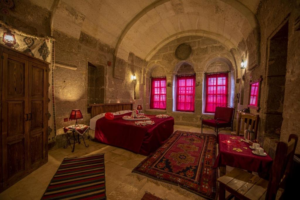 Guzelyurt卡帕多西亚古董吉维利洞穴酒店的卧室配有一张床和一张桌子