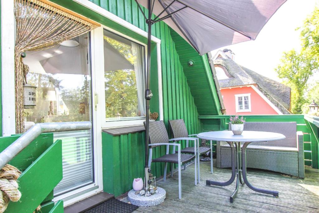 普雷罗Am Waldesrand的绿色房子,阳台上配有桌椅