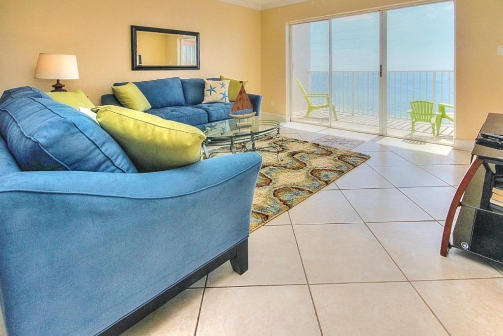 圣徒皮特海滩Sea Breeze 702的客厅配有蓝色的沙发和玻璃桌