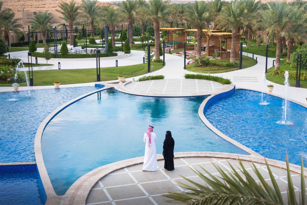 利雅德Dorat Najd Resort的站在游泳池前的新娘和新郎