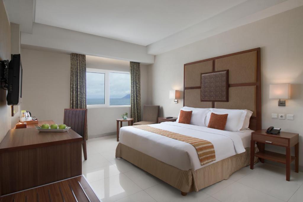 美娜多ASTON Manado Hotel的酒店客房设有一张大床和一张书桌。