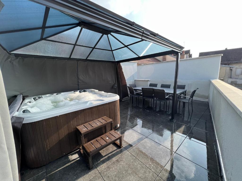 尚帕尼奥勒Appartement haut de gamme avec Jacuzzi Champagnole的阳台的热水浴池和遮阳伞