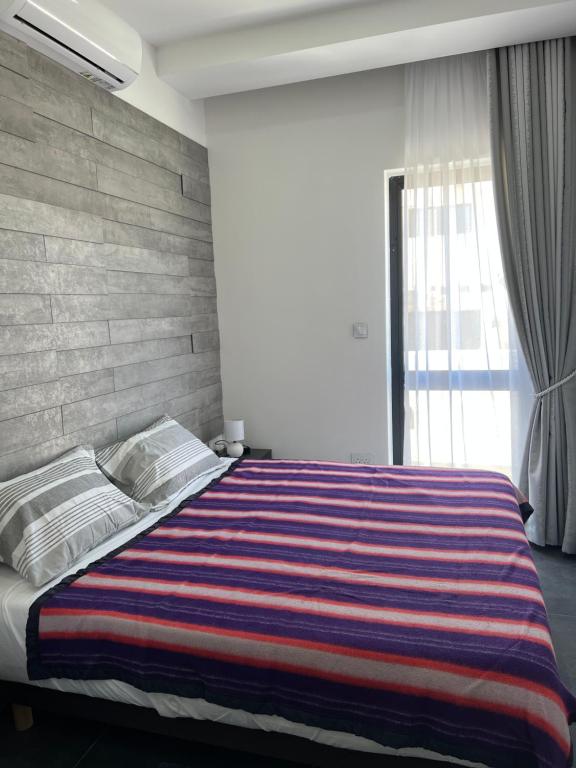 圣保罗湾城Cosy & Modern Top Floor 1-bedroom Apartment的一间卧室配有一张带条纹毯子的大床