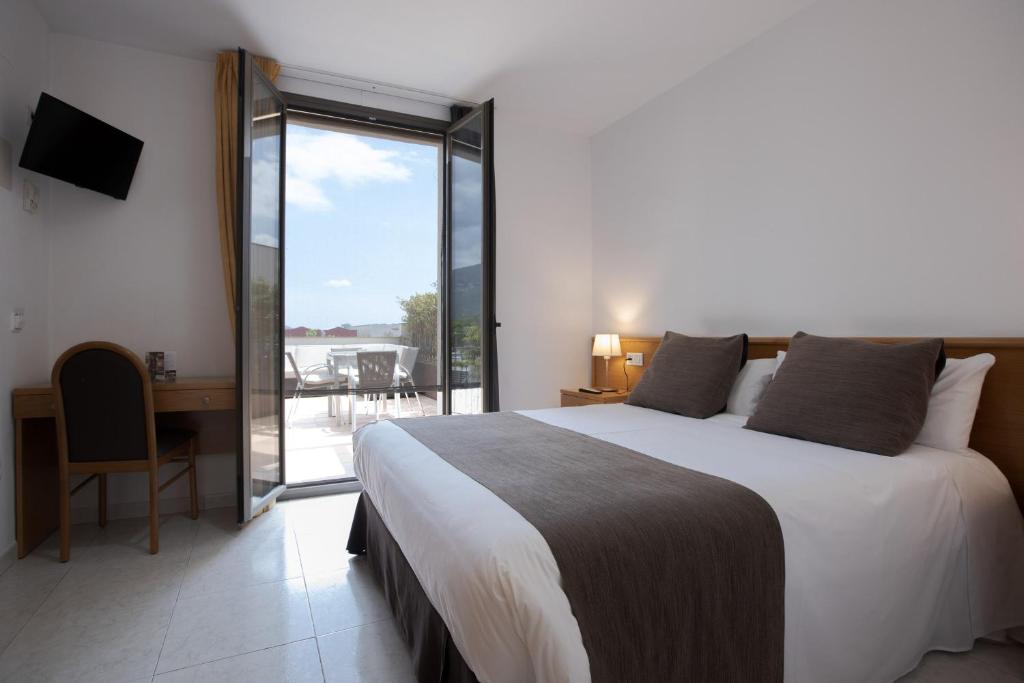 托尔特利亚阿尔塔格罗塔萨旅馆的一间带一张床和一张书桌的卧室以及一个阳台