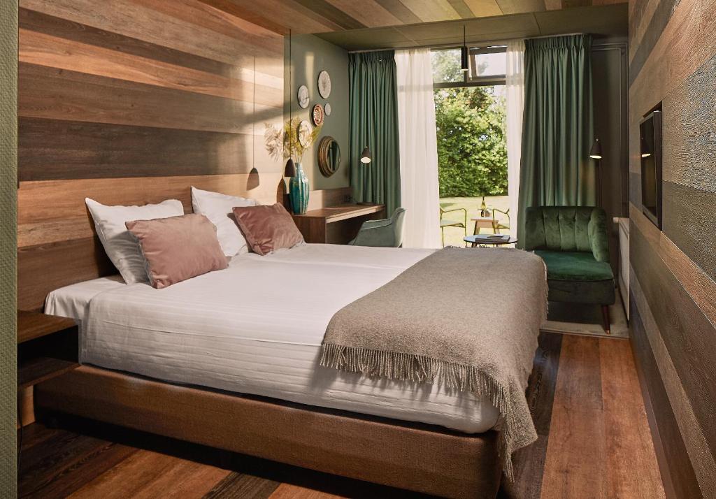Oost亨德里克特克塞尔王子酒店的一间卧室配有一张大床和一张绿色椅子