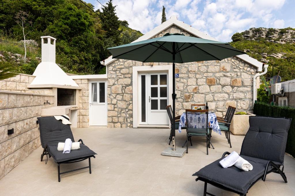 ProžuraPERLA - small comfy house with the terrace的庭院配有遮阳伞、椅子和桌子。