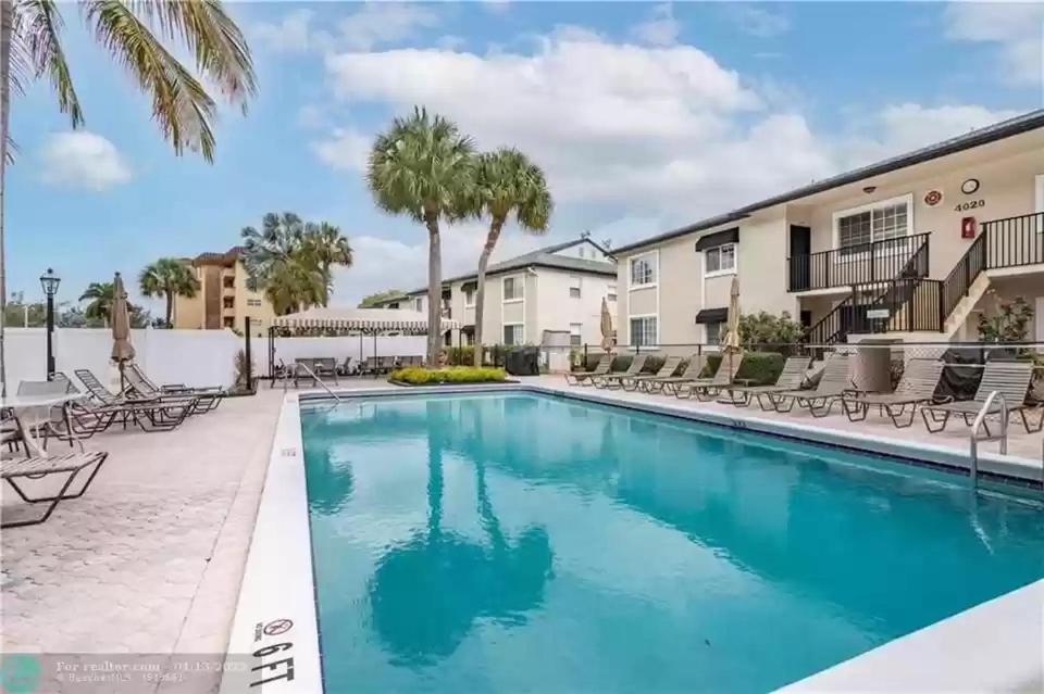 帕诺滩lovely 2BED 2BA vacation rental near the Beach的公寓的游泳池设有椅子和棕榈树。