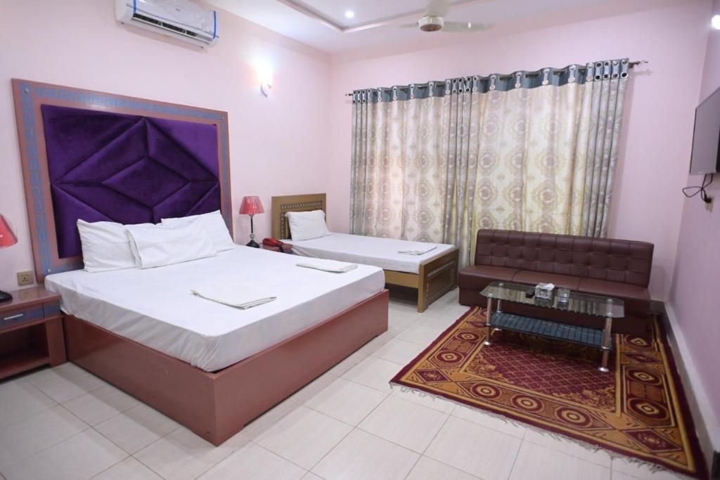 木尔坦Hotel Shaheen Continental Multan的一间卧室配有一张床、一张沙发和一张桌子