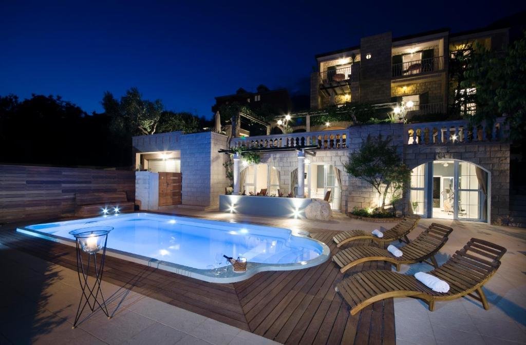 图彻皮Villa Bougenvilia Tomas的一座带椅子的游泳池,一座夜间建筑