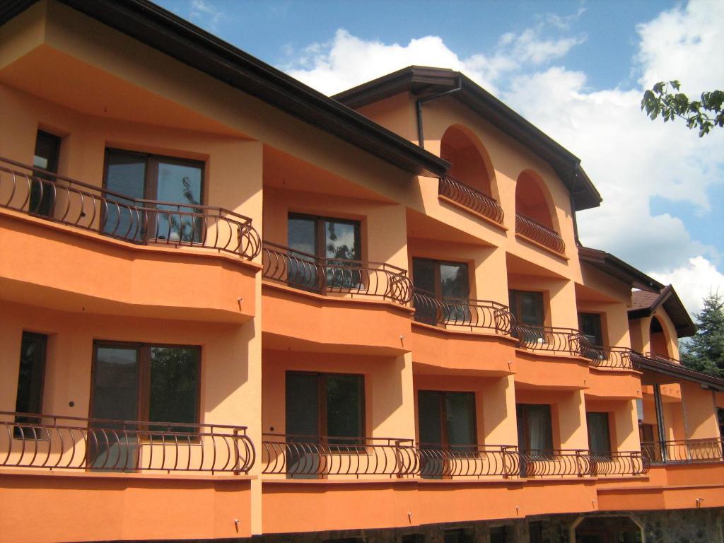 萨帕雷瓦巴尼亚Family Hotel Emaly Green的一座橙色的建筑,旁边设有阳台
