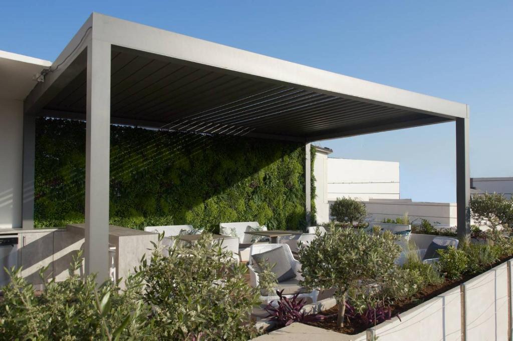 海若克利欧7Rizes Luxury Living的一个带白色椅子和植物的有盖庭院