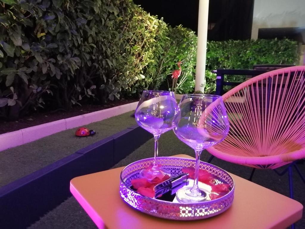 第戎Romantisme et glamour 2 avec spa , clim et jardin的两杯酒杯坐在桌子上盘子上