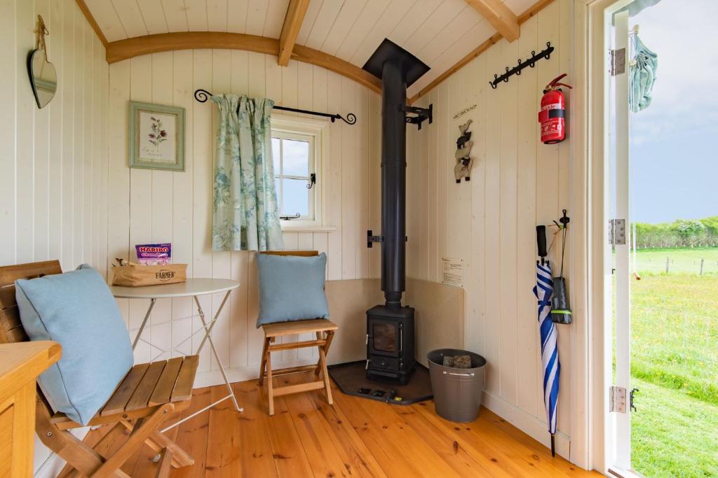 埃杰顿Mist Sheperd's Hut by Bloom Stays的一间带炉灶、两把椅子和一张桌子的房间