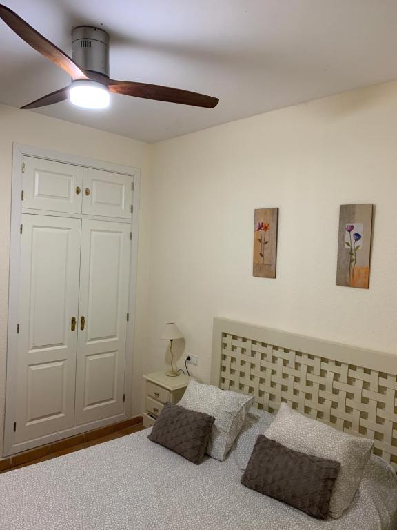 伊斯兰蒂拉Apartamento en islantilla的一间卧室配有一张带两个枕头的床和吊扇