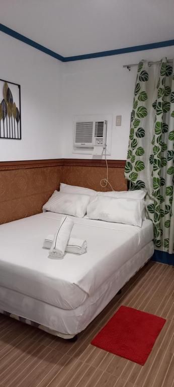 CompolCamiguin VIAJEROS House Rental的卧室配有白色床和红色地毯