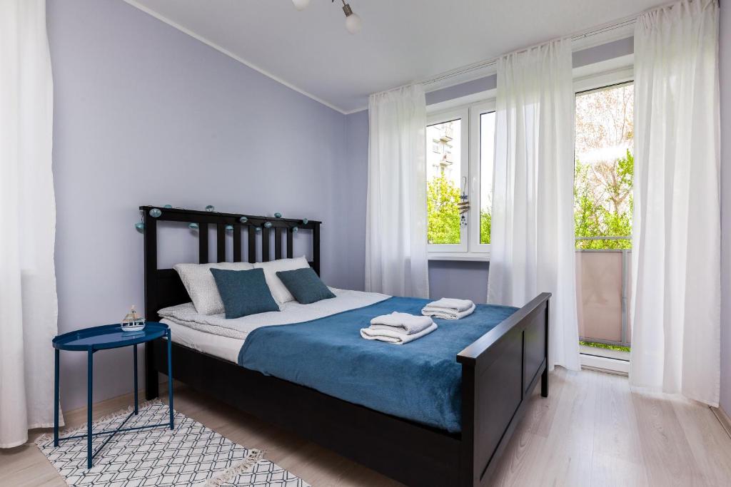 格丁尼亚Prime Home PARKOWY的一间卧室配有一张带蓝色床单和窗户的床。