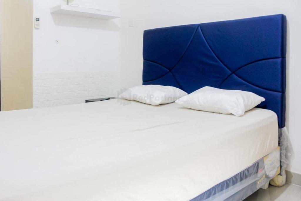 雅加达RedLiving Apartemen Paradise Mansion - Gunawan的一张带蓝色床头板和两个白色枕头的床