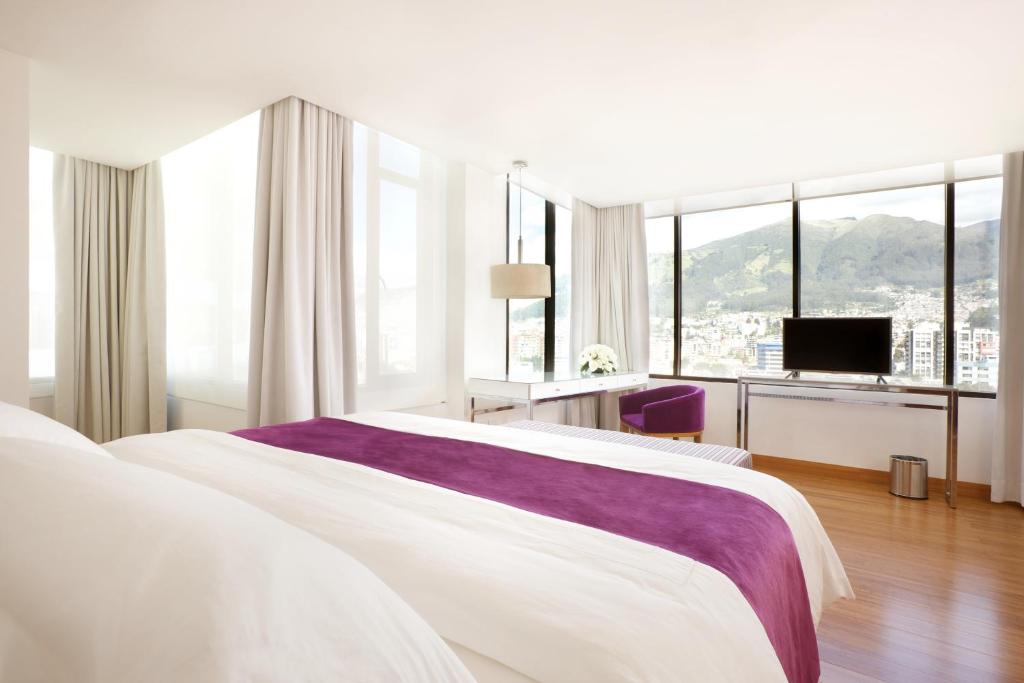 基多里约亚马逊酒店的白色卧室设有一张大床和电视。