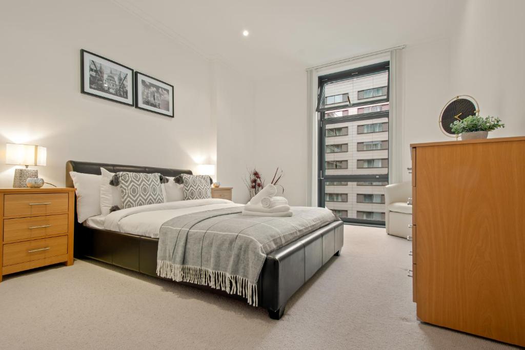 伦敦South Quay Apartments Canary Wharf的一间卧室配有一张床、一个梳妆台和一扇窗户。