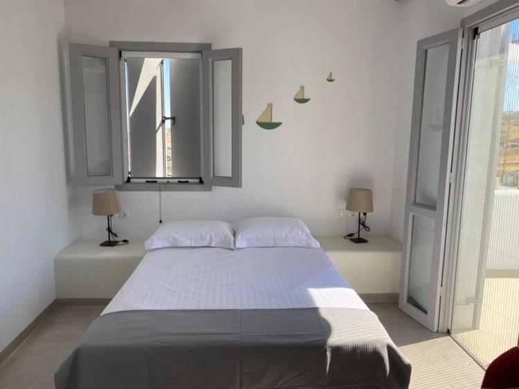 基莫洛斯岛Maganiotis Rooms的一间卧室设有一张大床和两个窗户