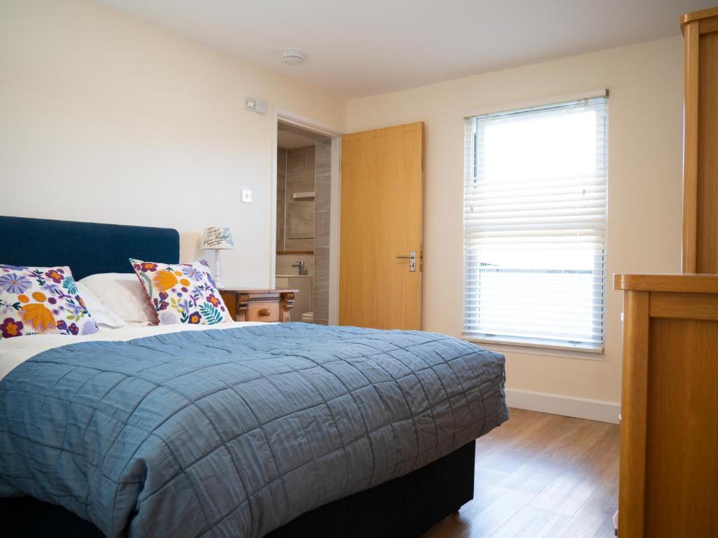 瓦利Ellingham Apartments, Bordeaux Harbour, Guernsey的一间卧室配有一张带蓝色毯子的床和窗户。