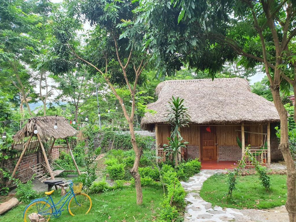 宁平Ninh Binh Bamboo Farmstay的一间有稻草屋顶的小房子,前面有一辆自行车