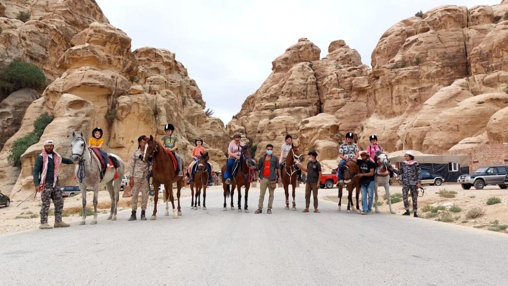 瓦迪穆萨Petra Royal Ranch的一群在沙漠里骑着马的人