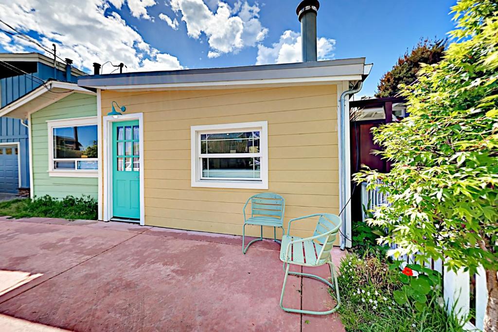 圣克鲁兹Beach Haven的黄色的房子,有蓝色的门和两把椅子