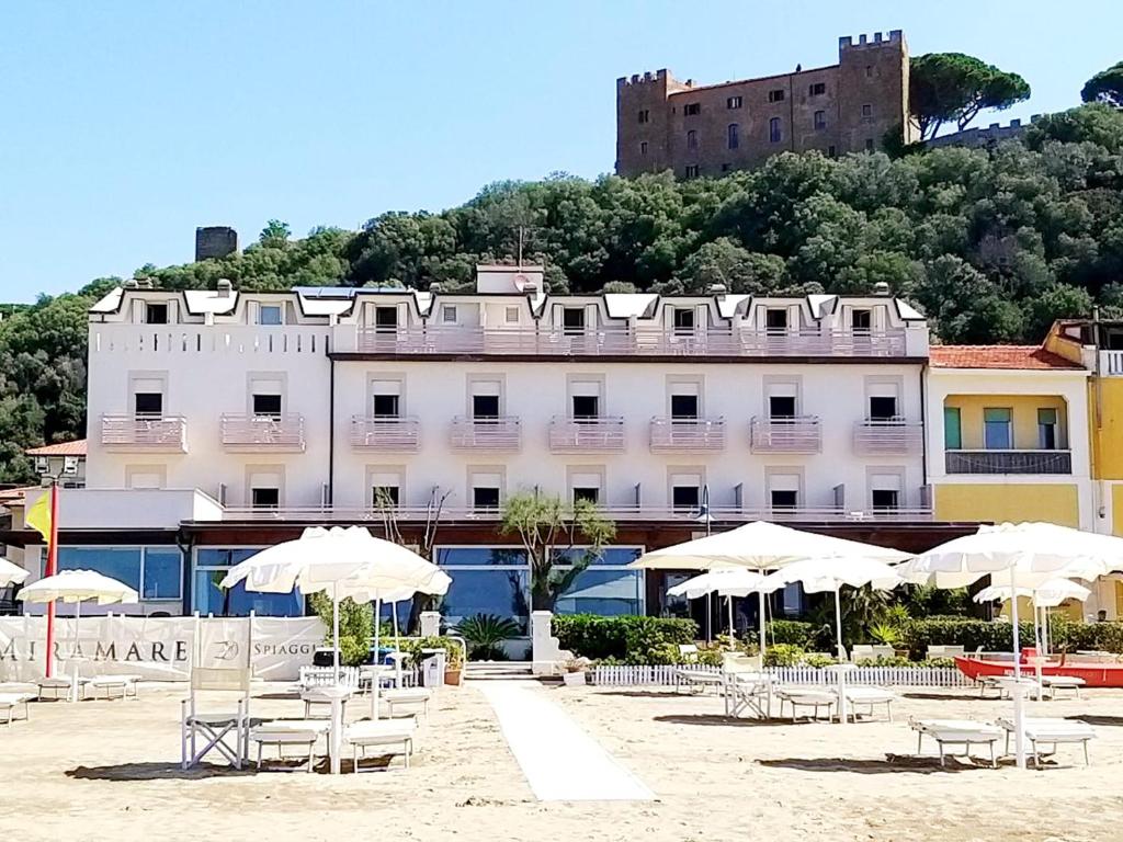 卡斯蒂里昂纳·德拉佩米拉马雷酒店的海滩上一座带椅子和遮阳伞的建筑
