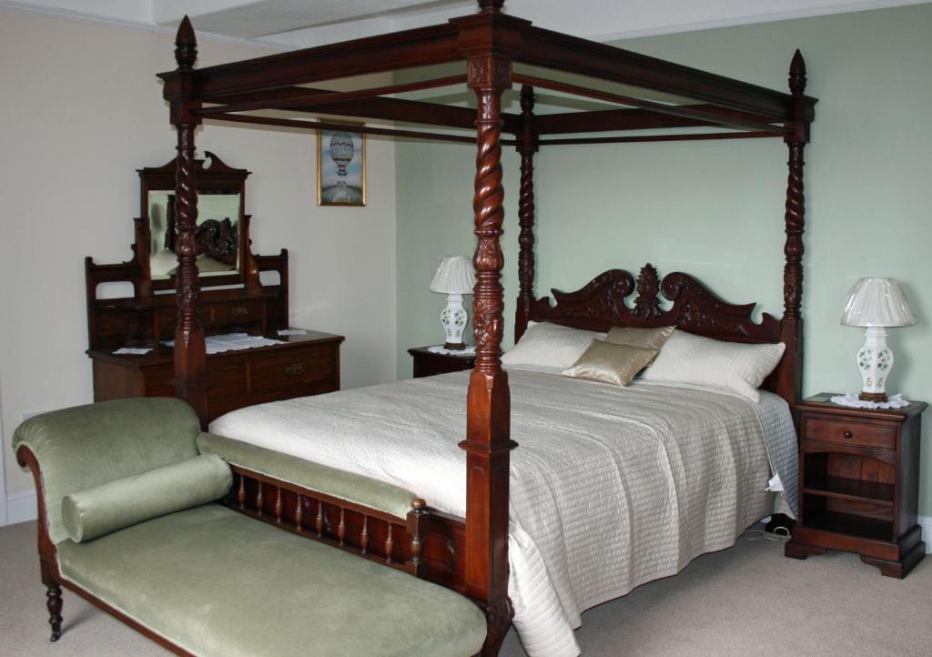 赖厄德Penralley House B&B的一间卧室配有一张天蓬床和一把椅子