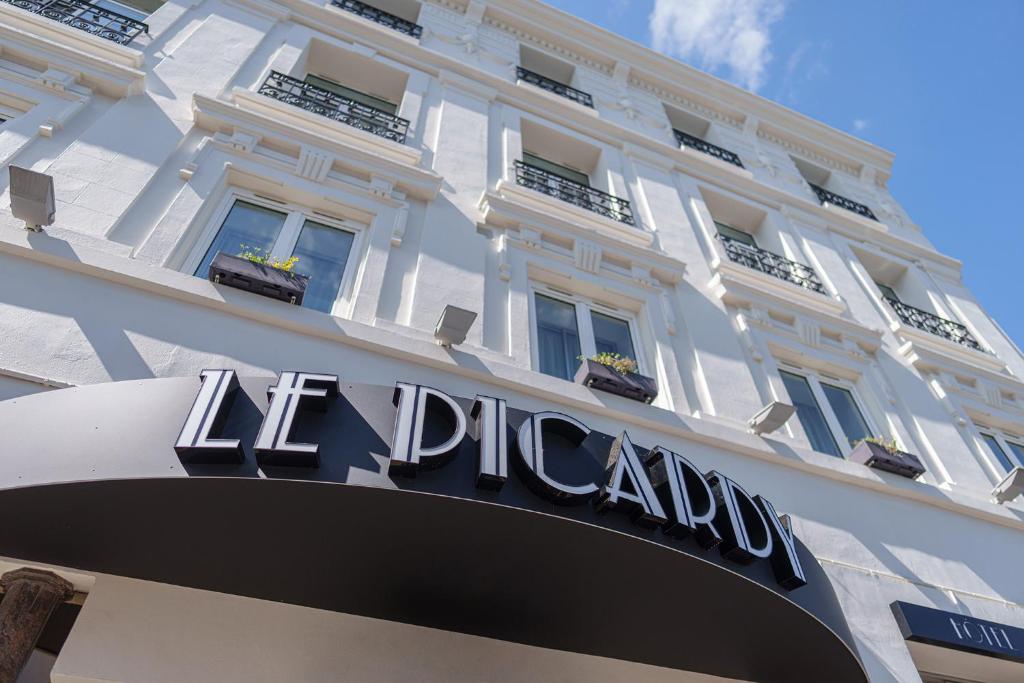 圣康坦Hôtel Le Picardy的一座白色的大建筑,上面有标志