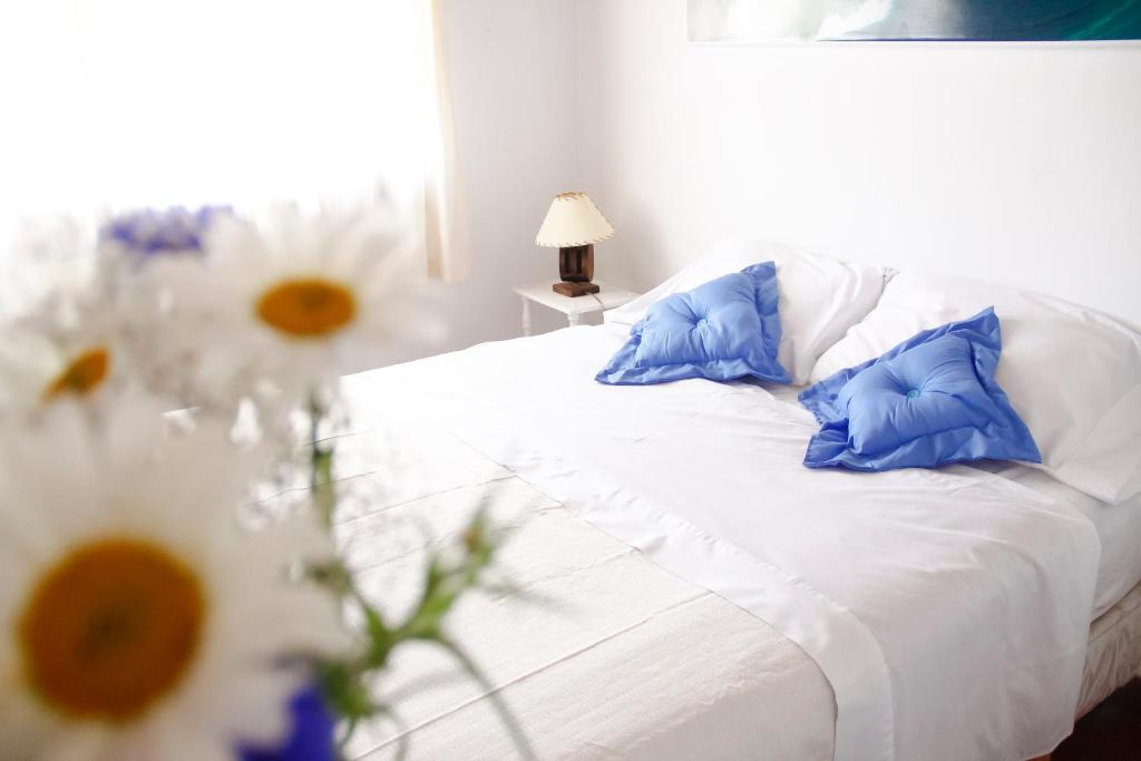 耶尔瓦布埃纳A Alquiler temporario Arrullo de Luna的一张白色的床,上面有蓝色的枕头和鲜花