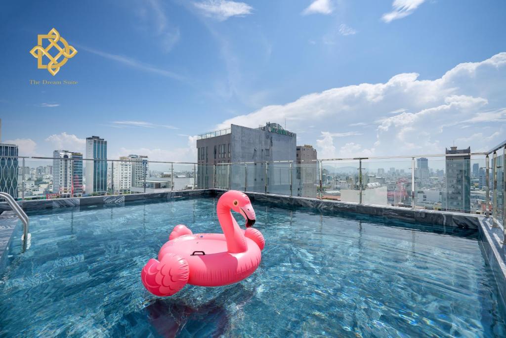 岘港The Dream Suite的粉色天鹅浮在一座建筑物顶部的游泳池里