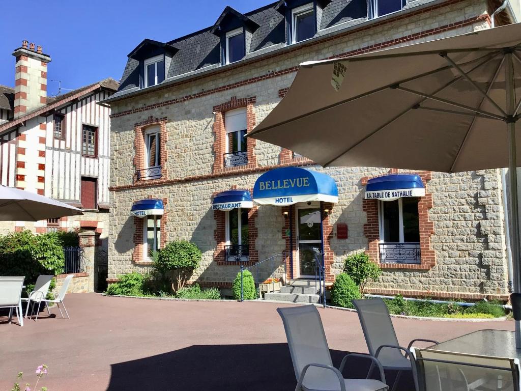 巴尼奥勒德日洛恩Hôtel Bellevue Bagnoles Normandie的前面有一把伞和椅子的建筑