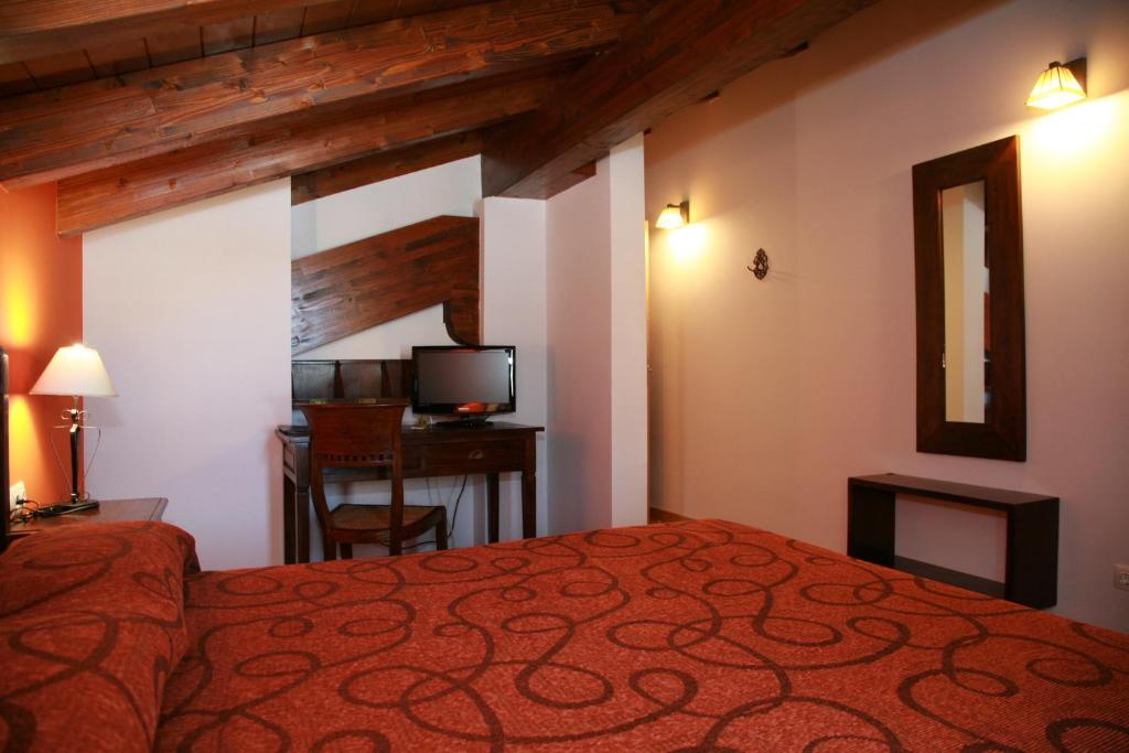 Maturana拉卡萨维亚旅馆的一间卧室配有一张床、一张书桌和一台电视