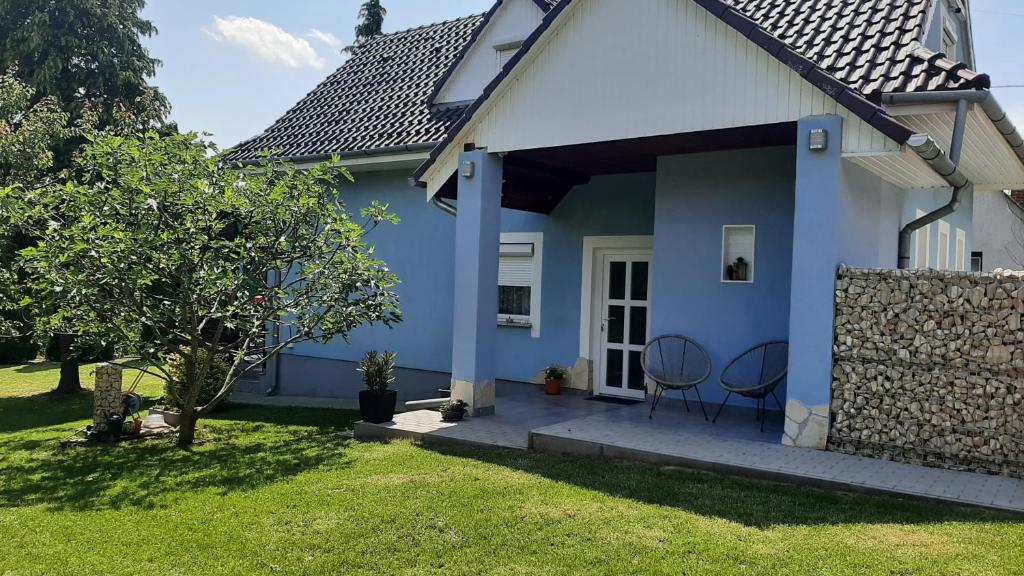 佐洛卡罗斯Jenny vendégház的蓝色和白色的房子,门廊上摆放着两把椅子