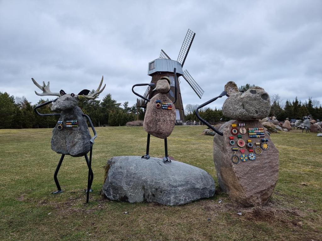 KaralaMardi Farm Stay的一座三头驼鹿的雕像,站在一块岩石上,有风车